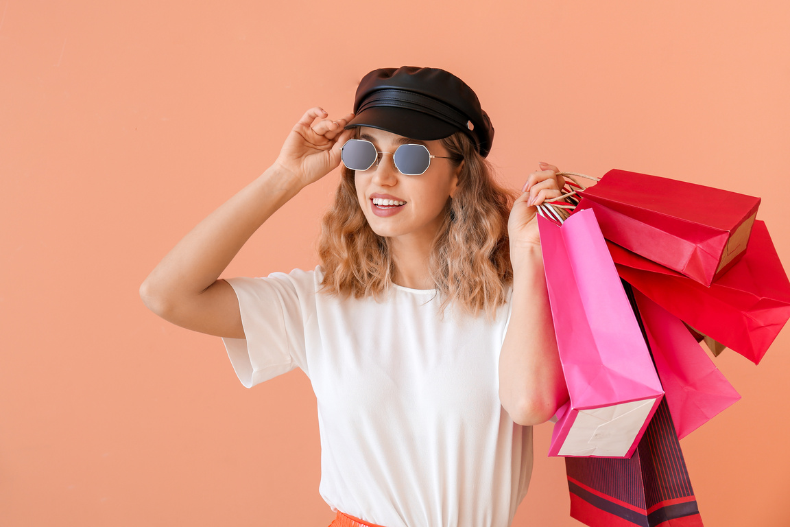 Beautiful Young Woman with Shopping Bags on Color Background